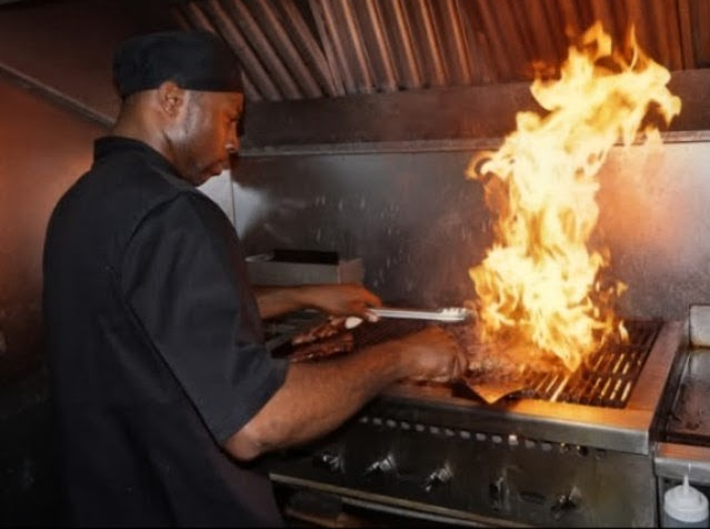Chef Whittaker cooking beside a rising live flame